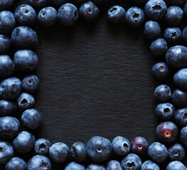 Wall Mural - Photography of blueberries on slate background for messages, menus, labels or signs in a square copy space