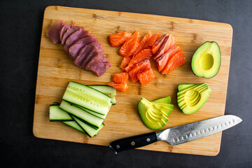 Wall Mural - Slicing Fresh Fish and Vegetables to Make Sushi: Sliced fish, avocado, and cucumber on a bamboo cutting board