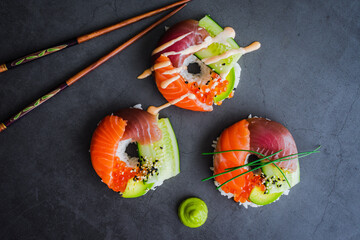 Wall Mural - Salmon and Tuna Sushi Shaped into Donuts with Wasabi Paste: Fresh sushi shaped into rings and garnished with spicy mayo, chives, and sesame seeds