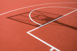 © vejaa - Shadow of the rack with shield and basketball ring on orange basketball rubber field ground during sunny day outdoors. Basketball game background