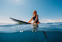 Attractive Surf Girl Sit On Surfboard In Ocean.