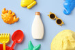 Baby sun protection concept. Sunscreen cream, sunglasses, sand molds, panama hat on blue background. Flat lay, top view.