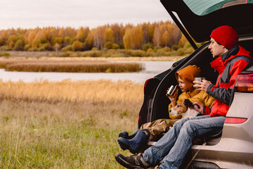 family traveling by car having rest and looking at beautiful fall landscape