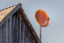 Rusty Satellite Dish On Wooden Gable Roof