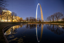 Reflection Of Glowing Gateway Arch Of St. Louis With Spot Lights On Surface Of Lake At Sunset Time On National Park