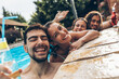 © BalanceFormCreative - A group of young people refreshing in the swimming pool and toasting together with cold drinks.