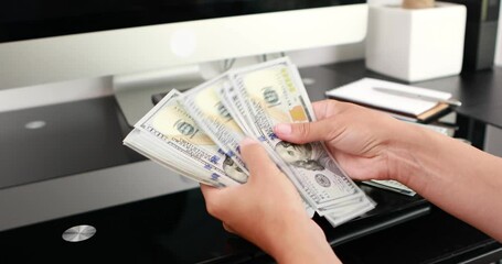 Wall Mural - close-up of woman hands counting a stack of hundred-dollar US banknotes.