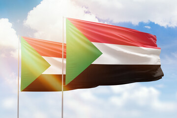 Sunny blue sky and flags of sudan and sudan