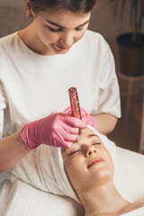 Wall Mural - close-up portrait of beautician doing hydra facial microdermabrasion procedure in spa salon. female 