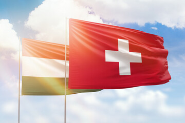 Sunny blue sky and flags of switzerland and hungary