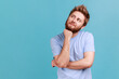 © khosrork - Portrait of smiling happy bearded man looking away with pensive expression, dreaming pleasant thoughts, fantasizing and making wish. Indoor studio shot isolated on blue background.