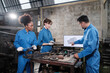 Three multiracial professional industry engineer workers teams in safety uniforms metalwork jobs discuss with mechanical drawing in a monitor, lathe machines, and workshop in manufacturing factory.