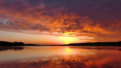 Wall Mural - Spectacular red dawn sky mirrored in tranquil waters, dynamic moving perspective.
