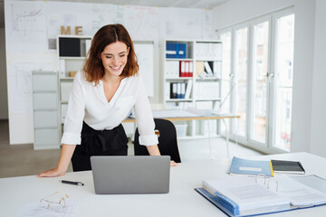 Wall Mural - young business woman in office looking at her laptop