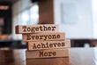 Wooden blocks with the word Together, Everyone, Achieves, More. Teamwork and team concept. Community, support, partnership. Achieving a common goal. Cooperation and business strategy