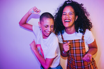 Wall Mural - Two female friends dancing together at a house party