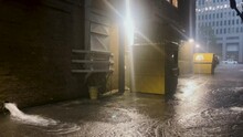 Urban alleyway and dumpsters in the early morning during a rainstorm looking south.