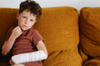 © ADDICTIVE STOCK - Cute boy with broken arm on couch