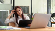 © Prathankarnpap - Serious asian female employee sitting in front of laptop and reading financial document