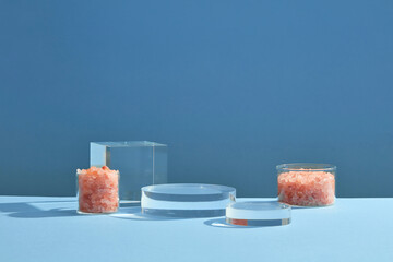 Wall Mural - Front view of himalaya salt decorated with transparent podium in blue background abstract