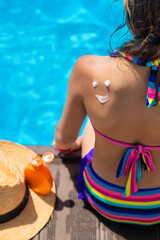 Poster - Child near the pool smears sunscreen. Selection focus.