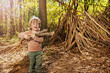 Boy with brushwood pile in the forest build hut of branches