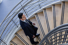 Businessman Walking Up Spiral Staircase In Office