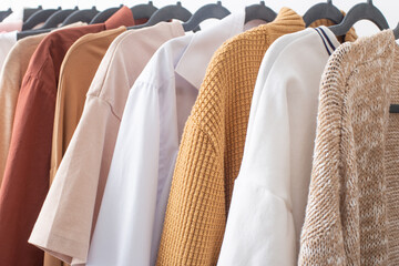 female autumn clothes on hangers  in  white room