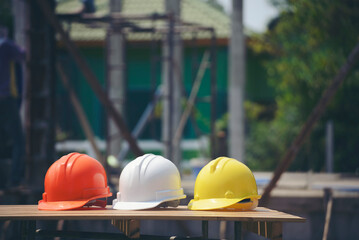 Wall Mural - Safety helmet (hard hat) for engineer, safety officer, or architect, place on cement floor. Yellow, White, and orange safety hat (helmet) in construction site.