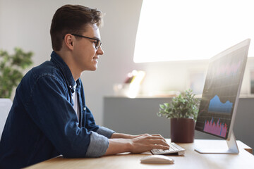 Poster - Profile Shot Of Young Businessman Working On Computer At Workplace In Office