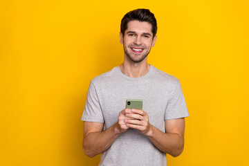 Wall Mural - Photo of optimistic brunet young guy hold telephone wear trend cloth isolated on yellow color background