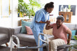 © Wavebreak Media - African american young doctor assisting senior female patient in getting up from sofa at home
