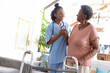 © Wavebreak Media - Smiling african american doctor holding senior patient's hand while standing at home, copy space