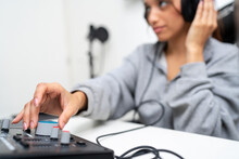 Female Audio Engineer Adjusting Knob In Recording Studio