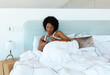 African american afro young woman having coffee on comfy bed at home, copy space
