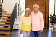 Portrait of smiling biracial senior friends standing against wooden door in nursing home