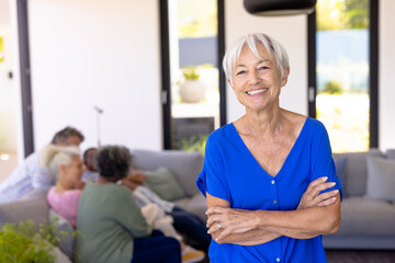 Wall Mural - Portrait of happy asian senior woman with arms crossed standing against multiracial friends