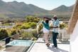© WavebreakMediaMicro - Multiracial senior friends doing salsa dance in balcony against mountain during summer