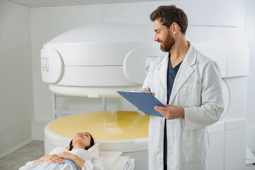 Wall Mural - Radiologist controls MRI or CT or PET Scan with female patient undergoing procedure