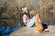 © Sophiaarenasphoto - Mujer adulta sentada junto a un perro mascota en el muelle del lago en el bosque