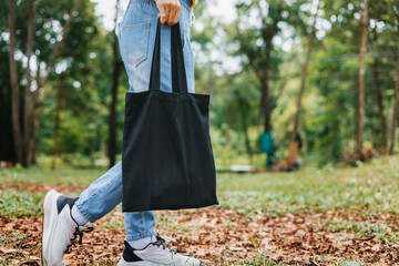 woman holding black cotton bag in nature background