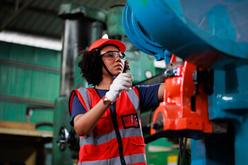 Wall Mural - Woman worker wearing safety goggles control lathe machine to drill components. Metal lathe industrial manufacturing factory