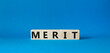 Merit symbol. Concept word Merit on wooden cubes. Beautiful blue background. Business and Merit concept. Copy space.
