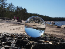 Coast Of The Gulf Of Finland. Crystal Ball In The Foreground And The Beach, Rocks, Sea And Pine Forest On The Horizon. Leningrad Region, Russia.