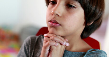 Boy praying to God with hands held together. Mixed race child prays spiritually faithful belief