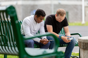 two men sitting on a park bench praying together