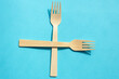 Wooden eco bamboo cutlery spoon and fork on bright blue background. Meal time concept