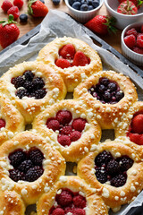 Wall Mural - Homemade sweet yeast buns with the addition of blackberries, blueberries, strawberries, and raspberries sprinkled  butter crumble, close up view