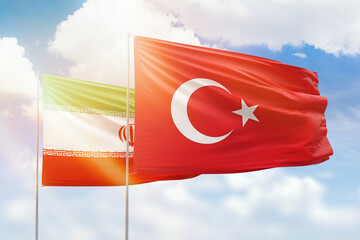 Sunny blue sky and flags of turkey and iran