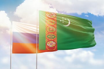 Sunny blue sky and flags of turkmenistan and russia